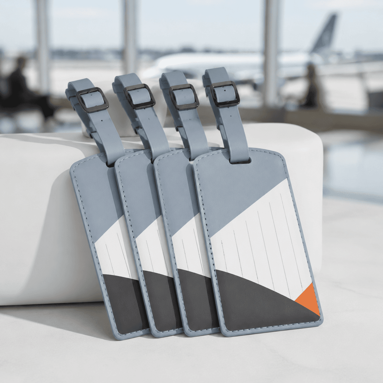 Set of four fog-blue luggage tags fanned out on a neutral studio backdrop